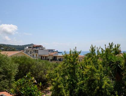 View of buildings and sea with lush vegetation.