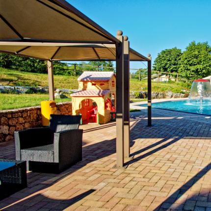 Piscina all'aperto con area giochi e vista montagna.