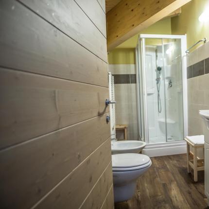 Bagno moderno con doccia, lavabo e bidet, pavimento in legno.