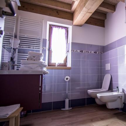 Bagno moderno con piastrelle viola e soffitto in legno.