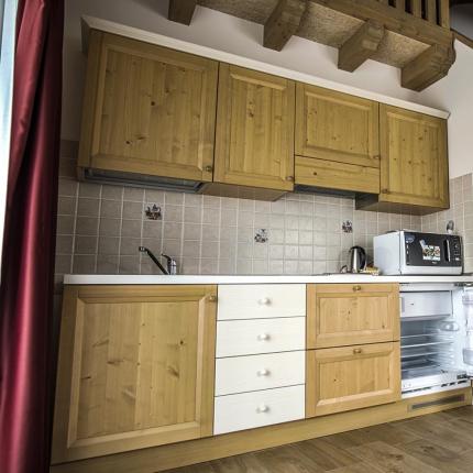 Cucina compatta in legno con microonde e frigorifero.