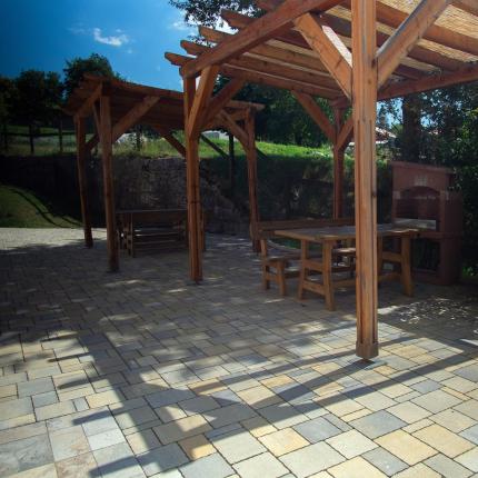 Gazebo in legno su pavimentazione in pietra, con tavoli e panchine.