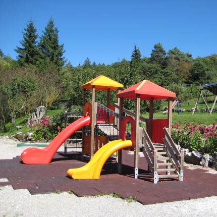 Parco giochi all'aperto con scivoli colorati e giardino fiorito.