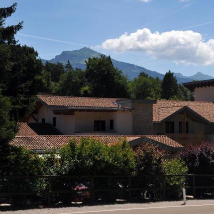 Casa con tetto in tegole, montagne e cielo azzurro.