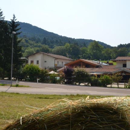 Paesaggio rurale con case, alberi e montagna sullo sfondo.