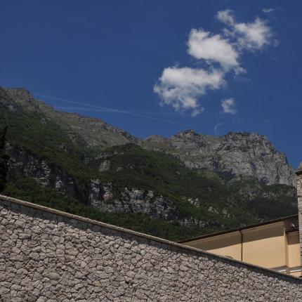 Chiesa con campanile e montagne sullo sfondo sotto un cielo blu.