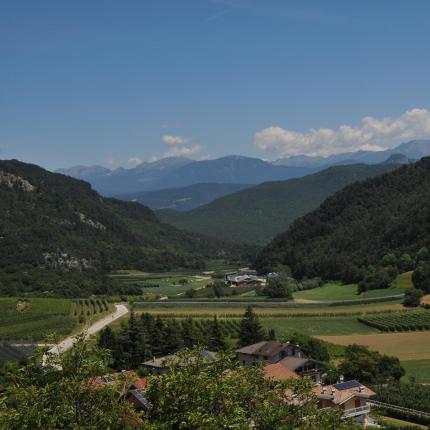 Valle verde con montagne e campi coltivati sotto un cielo azzurro.