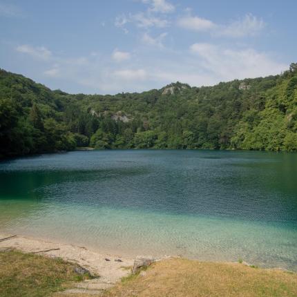 Lago sereno circondato da foreste verdi e colline.