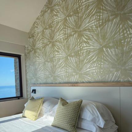 Helles Zimmer mit elegantem Bett, dekorativen Kissen und Meerblick.