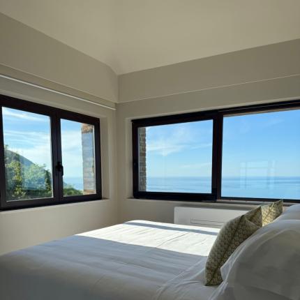 Helles Zimmer mit weißem Bett und entspannendem Meerblick.