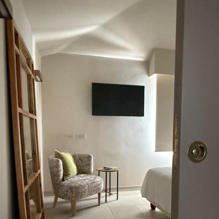 Gemütliches Zimmer mit Sessel, grünem Kissen und sanftem Licht.