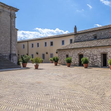 Sunny courtyard with historic buildings and potted plants.