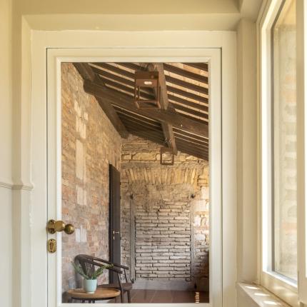Door to a rustic hallway, exposed bricks, warm light.