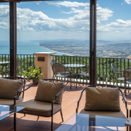 Scenic terrace with breathtaking sea and countryside view, blue sky, and clouds.