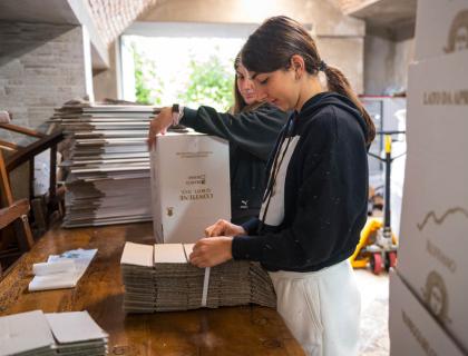 Due persone assemblano scatole con cura e dedizione in un ambiente artigianale.