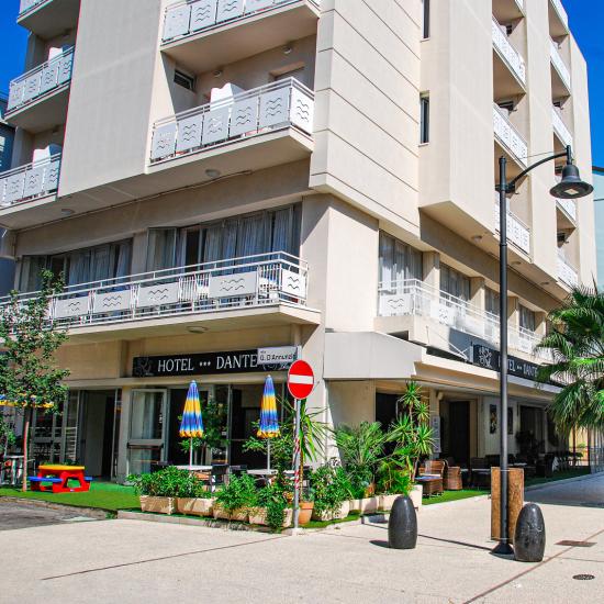 Strada pedonale con hotel e palme, cielo blu.