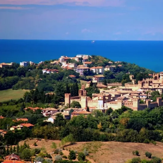 Castello medievale con vista sul mare e colline verdi.