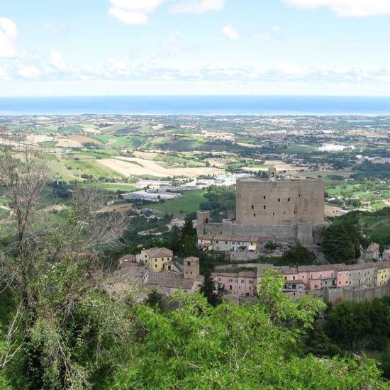 Castello medievale con vista panoramica su campagna e mare.