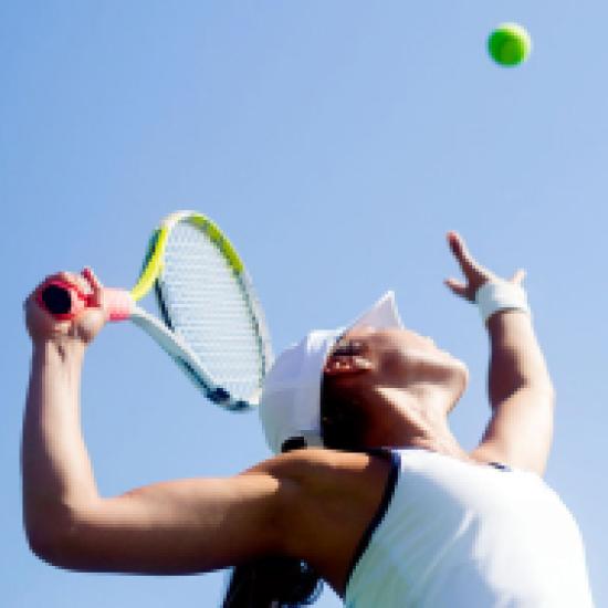 Giocatrice di tennis in azione mentre serve la palla.