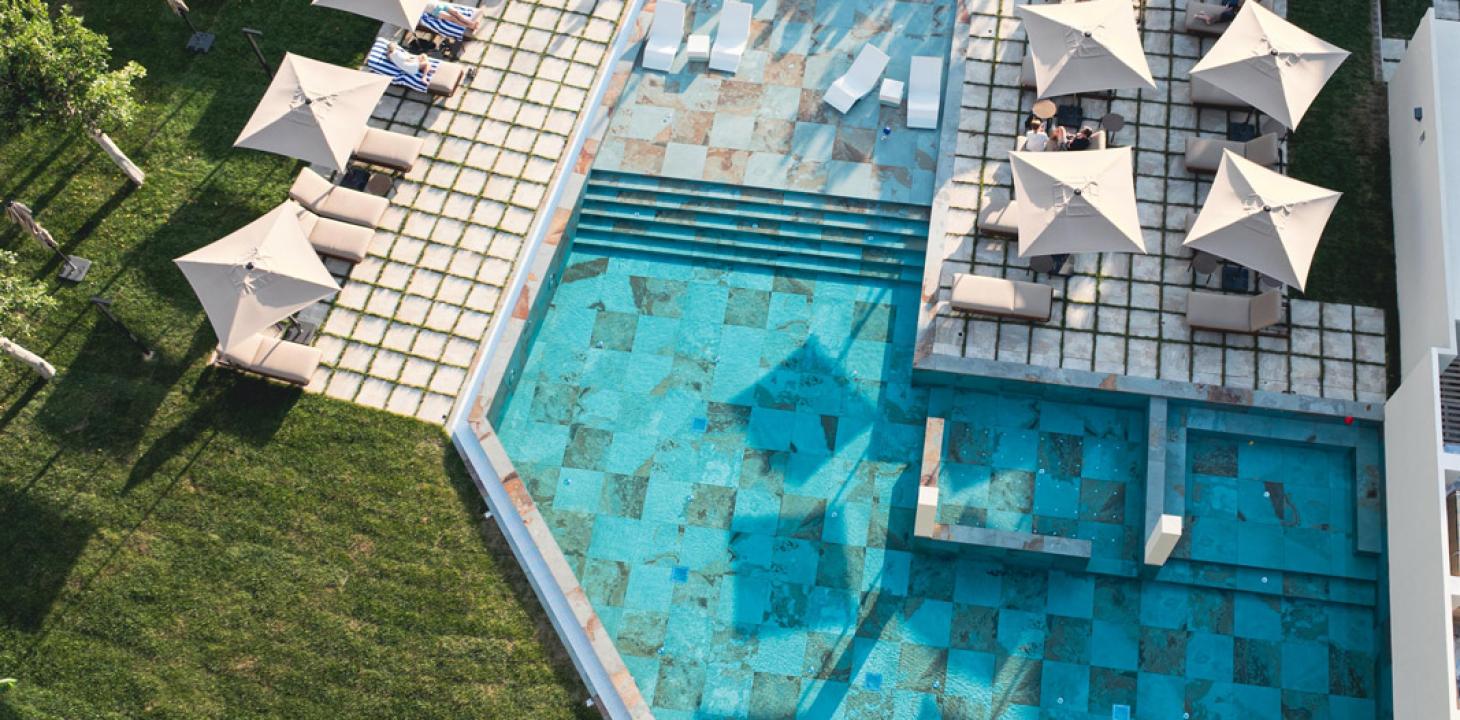 Piscina elegante con ombrelloni e lettini su prato verde, atmosfera rilassante e lussuosa.