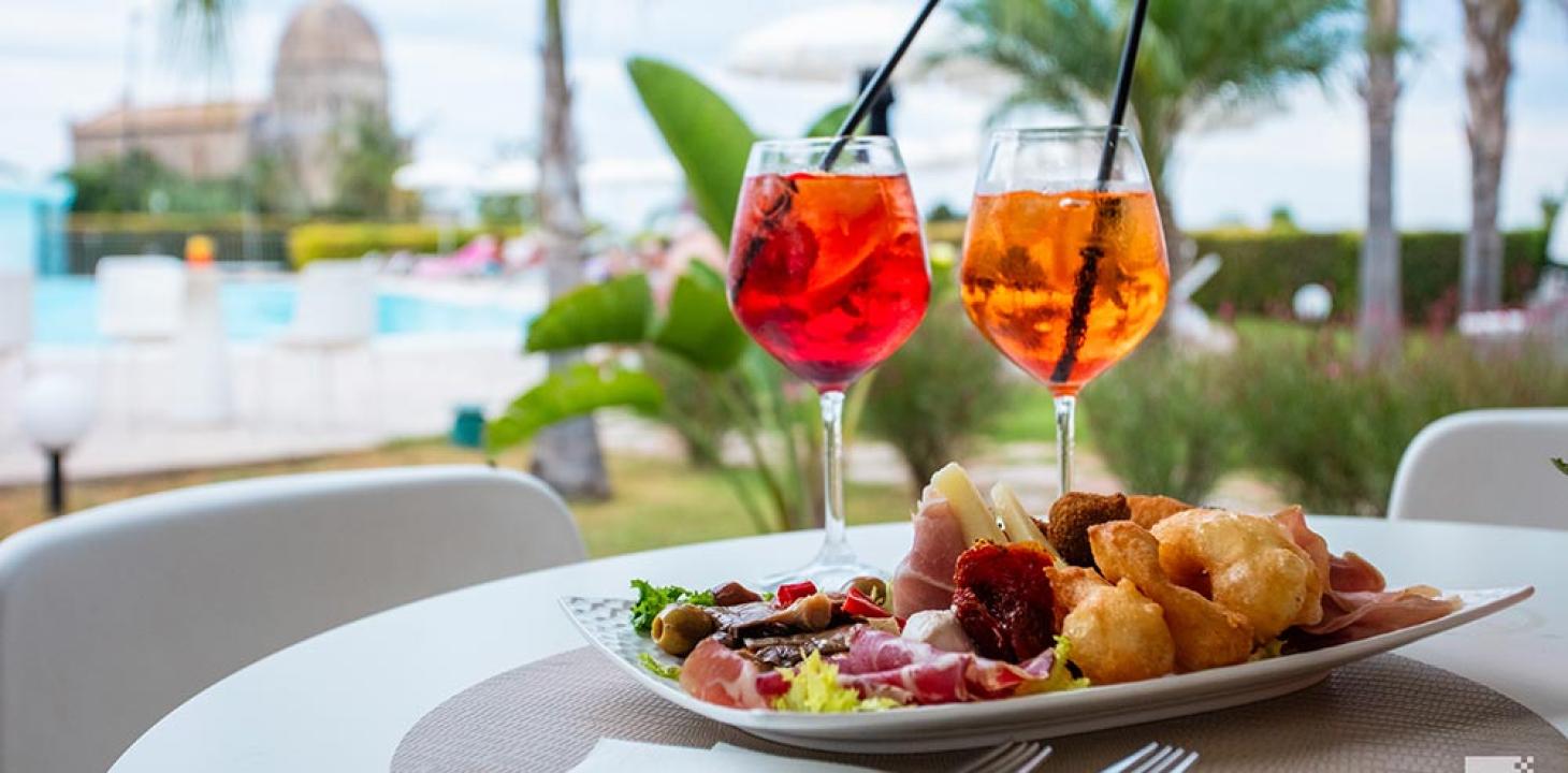 Aperitivo con Spritz e stuzzichini vicino alla piscina.