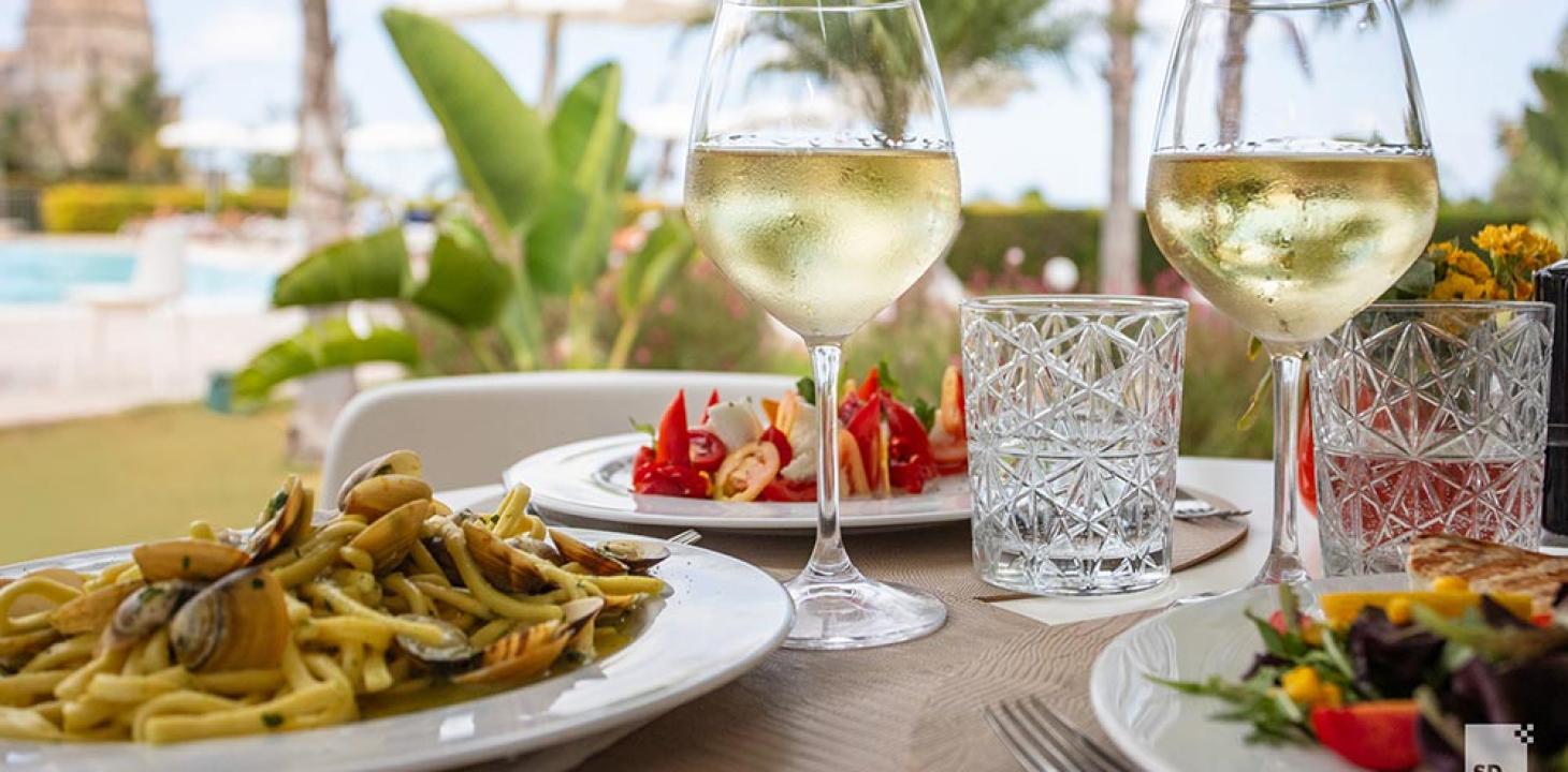 Pranzo all'aperto con vino bianco e piatti mediterranei.