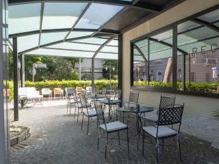 Sonnige Terrasse mit eleganten Stühlen, friedliche Atmosphäre und üppiges Grün.