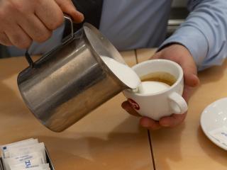 Hand gießt Milch in Kaffeetasse, schafft einen warmen Moment der Harmonie.