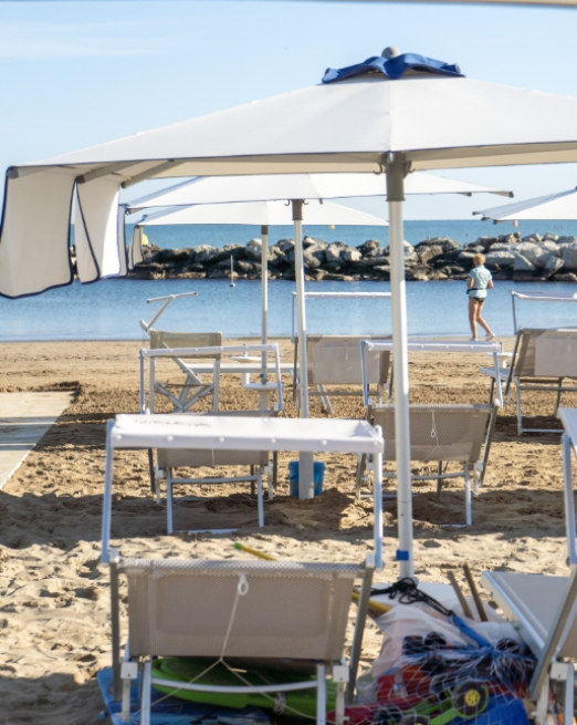 Spiaggia tranquilla, ombrelloni bianchi, mare calmo, atmosfera rilassante.