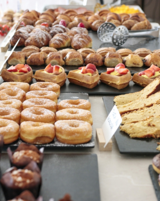 Deliziosi dolci assortiti: ciambelle, croissant, waffle con frutta, muffin e torte.