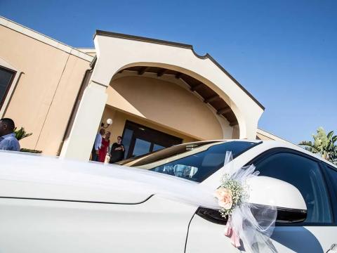 Decorated wedding car in front of elegant building.