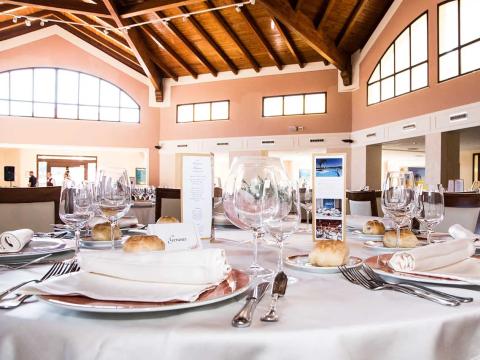 Elegant dining room with set tables and wooden ceiling.