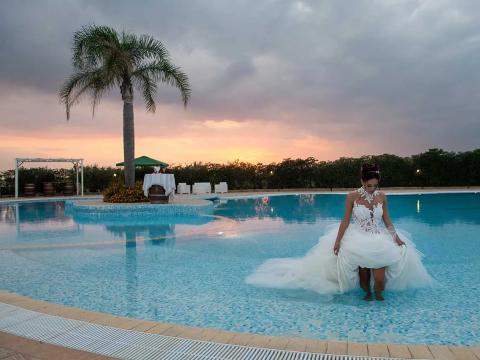 Bride in pool at sunset, creating a romantic and enchanting atmosphere.