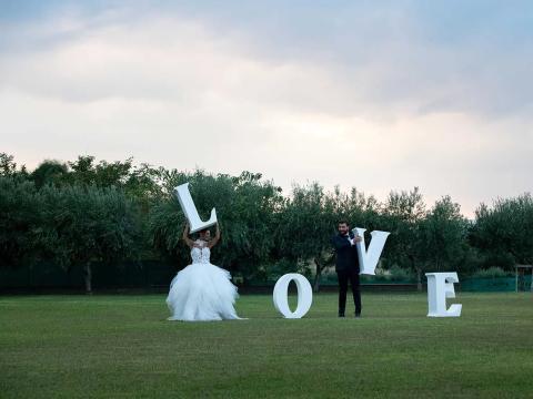 Couple with 'LOVE' letters on a lawn.