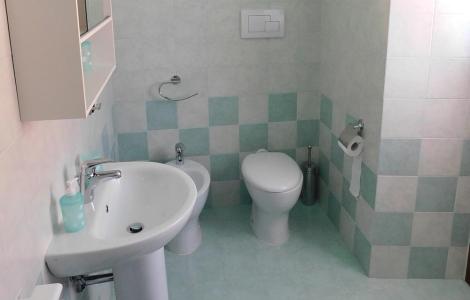 Bagno moderno con piastrelle verdi e sanitari bianchi.