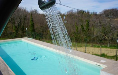 Doccia esterna vicino a una piscina in un ambiente naturale.