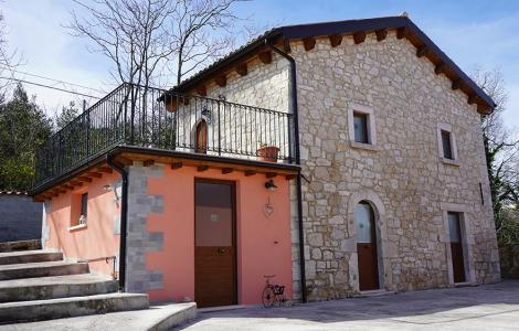 Casa in pietra con balcone e dettagli in legno.