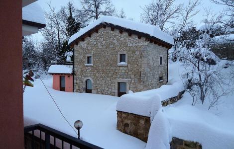 Casa di pietra coperta di neve, paesaggio invernale.