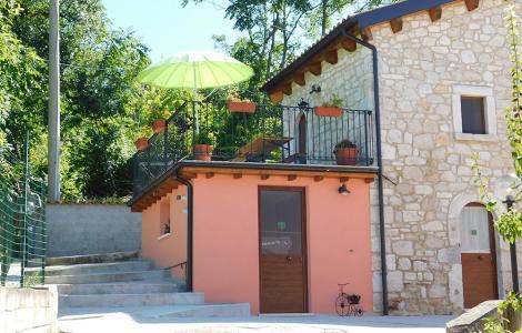 Casa in pietra con terrazza e ombrellone verde.