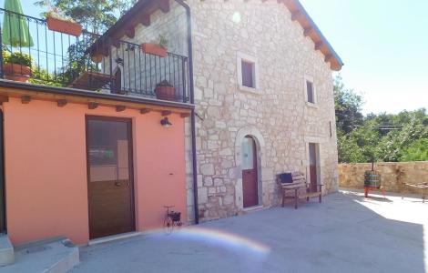 Casa in pietra con terrazza e piante in vaso.