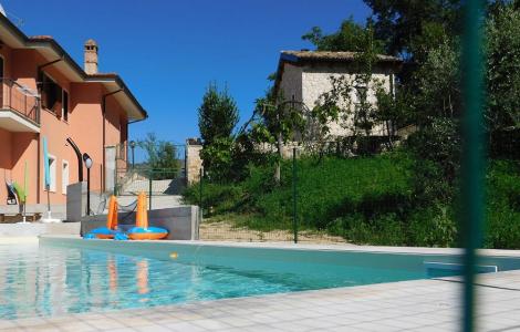 Piscina accanto a casa arancione e giardino verde.