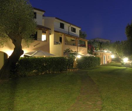 Giardino notturno con edificio illuminato e sentiero.