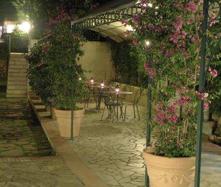 Giardino notturno con tavoli e piante fiorite.