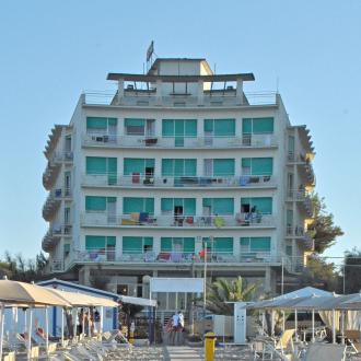 Edificio fronte mare con ombrelloni e sedie a sdraio sulla spiaggia.