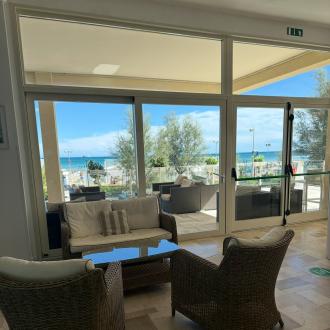 Salotto con vista mare, arredi in vimini, atmosfera rilassante.