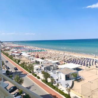 Spiaggia con ombrelloni colorati e mare calmo sotto un cielo limpido.