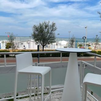 Vista mare con tavolo e sedie bianche su terrazza.