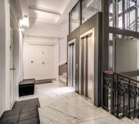 Elegant entrance with elevator and marble staircase.