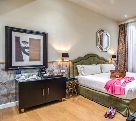 Elegant room with bed, suitcase, and artwork.