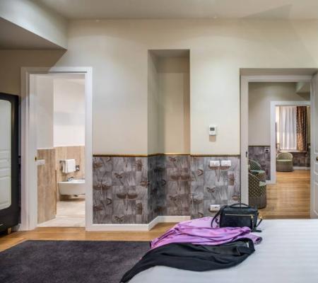Hotel room with bed, bathroom, and clutter on the nightstand.